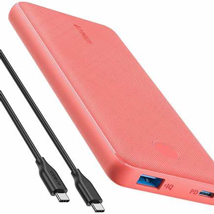 A coral-colored portable power bank with USB-A and USB-C ports, accompanied by two charging cables.
